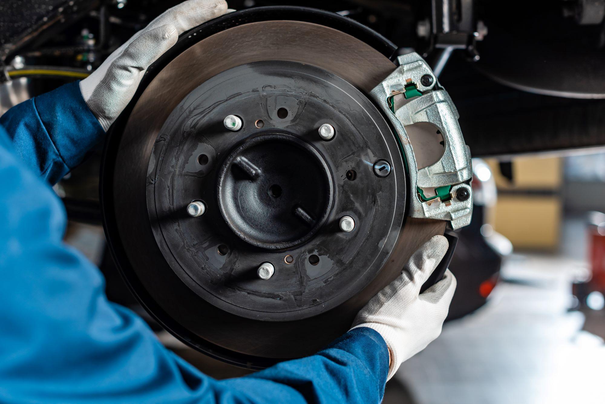 Gloved hands holding brake disc caliper, brake service Marco Island, FL
