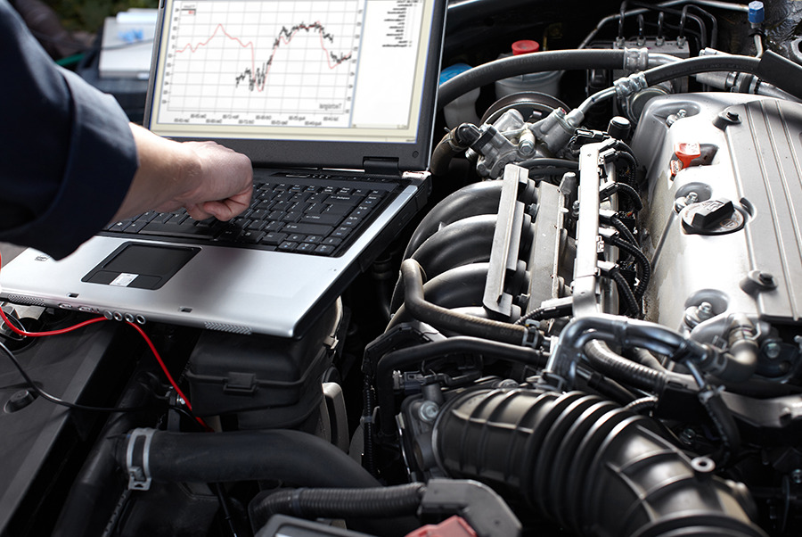 Automotive mechanic running laptop computer engine diagnostics in Naples, FL