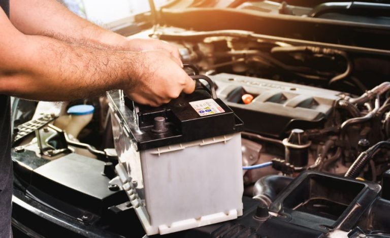 Local auto repair shop in Bonita Springs, FL showing mechanic installing a new 12V car battery