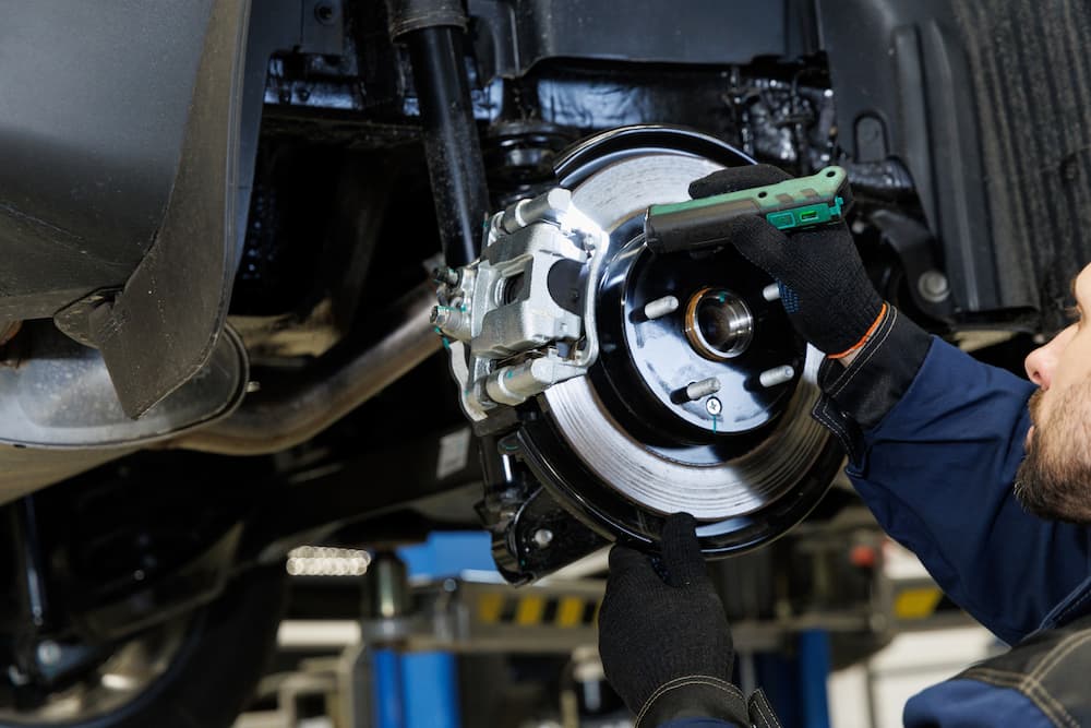 Mechanic inspecting a disc brake rotor during brake service in Naples, FL