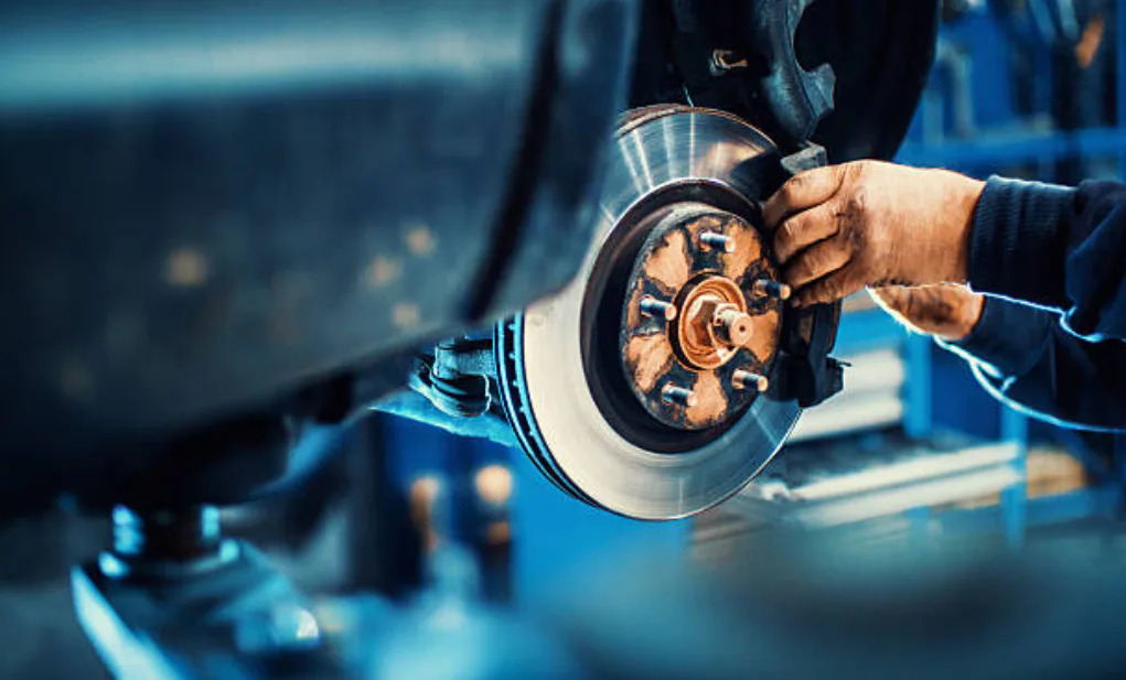 Professional brake inspection service in Bonita Springs, FL showing mechanic working on a rusted disc brake rotor assembly