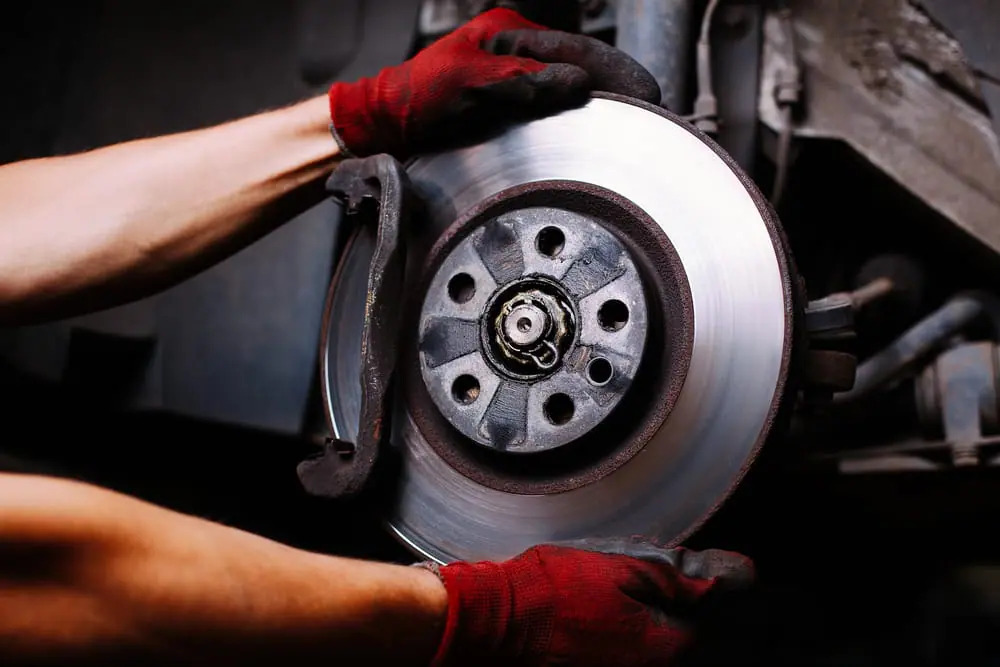 Brake disc repair service in Bonita Springs, FL featuring mechanic wearing red gloves aligning a clean brake rotor