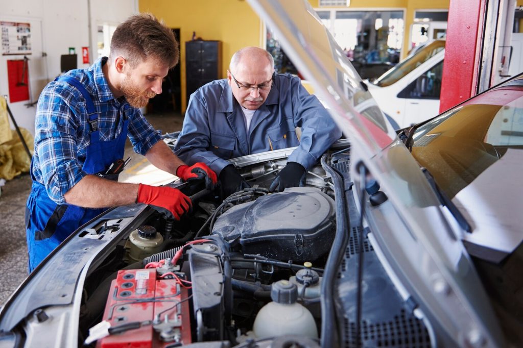 Two mechanics examining engine together, call us now Marco Island, FL