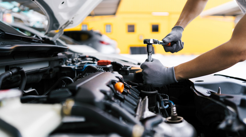 Mechanic using a socket wrench on a motor for engine repair in Naples, FL