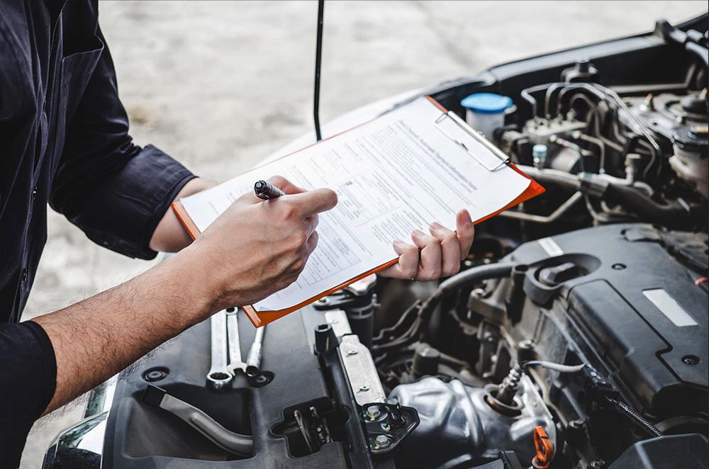 Auto technician filling out an inspection checklist during vehicle maintenance in Naples, FL