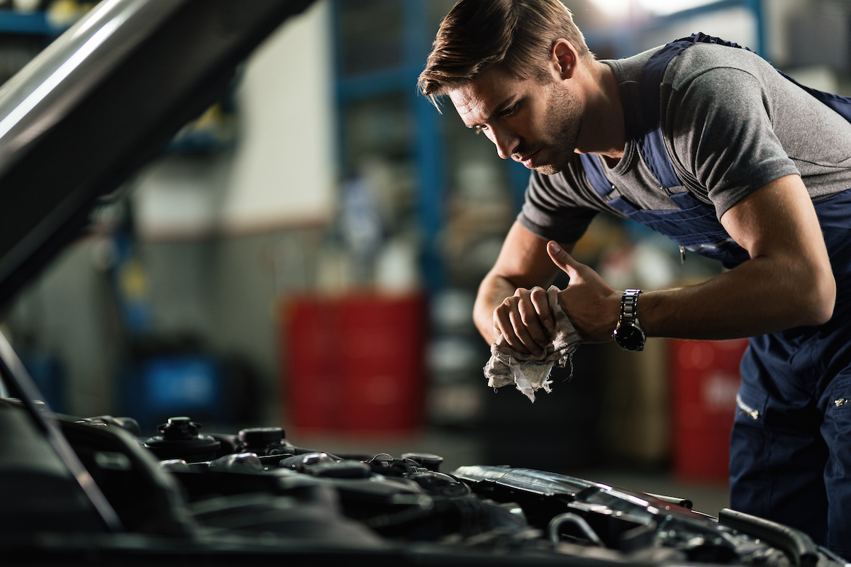 Routine vehicle maintenance service in Bonita Springs, FL showing mechanic wiping hands under open hood